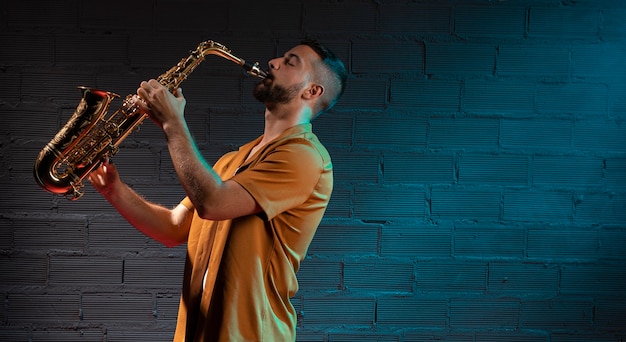 Мужчина-музыкант играет на саксофоне в центре внимания с копией пространства