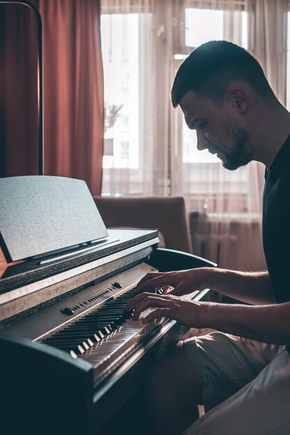 Male musician plays the electronic piano in the room