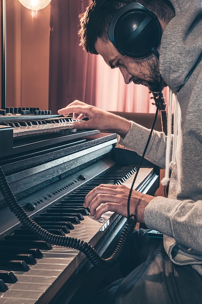 Мужчина-музыкант играет на музыкальных клавишах в наушниках