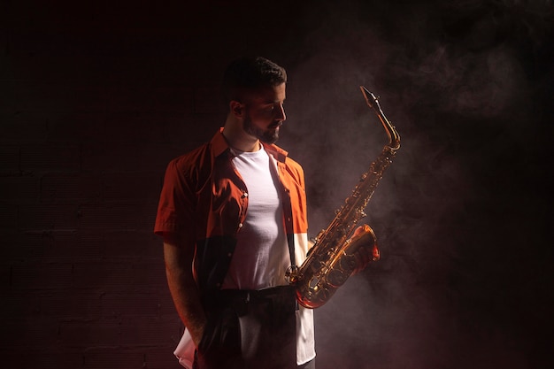 Free photo male musician in the spotlight holding saxophone