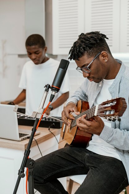 Male musicians at home playing guitar and electric keyboard