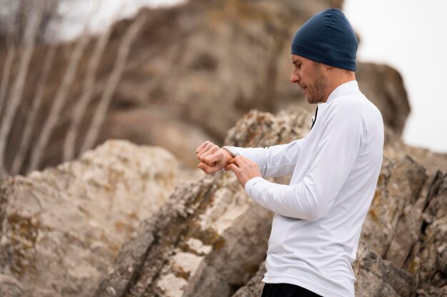 Male in nature looking at watch near rocks