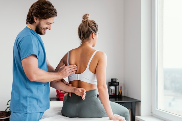 Male osteopathic therapist checking female patient's scapula bone