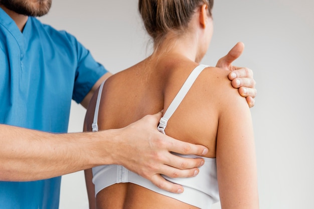 女性患者の肩甲骨をチェックする男性オステオパシーセラピスト