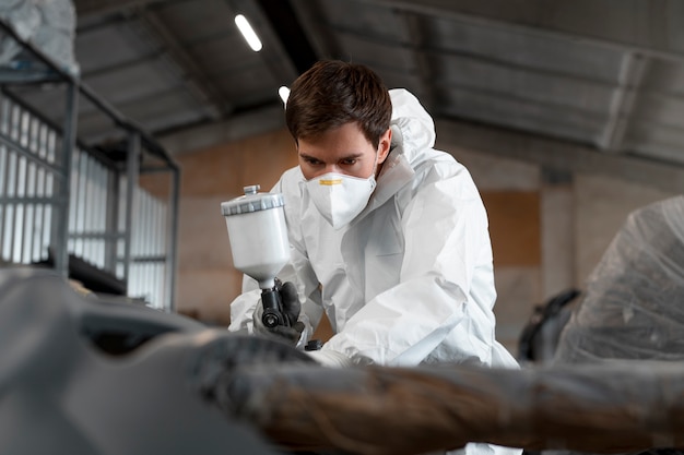 Male painter dressed in hazmat suit inside car shop