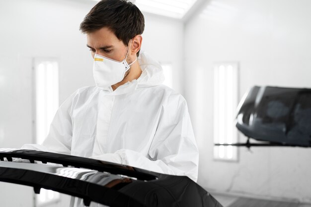 Free photo male painter in hazmat suit inside car shop