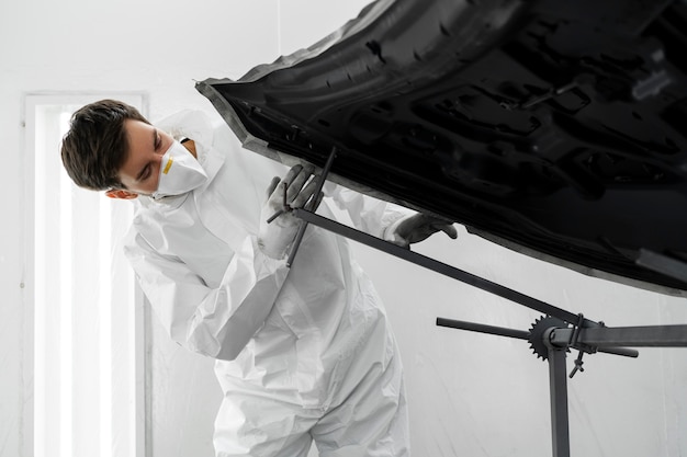 Free photo male painter in hazmat suit inside car shop