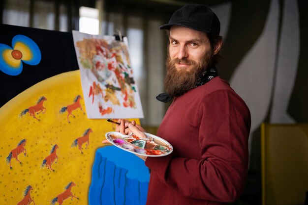 Художник-мужчина в студии, использующий акварель в своем искусстве