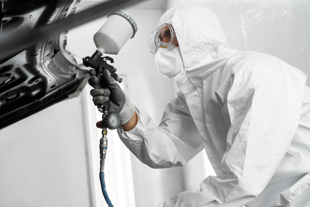 Free photo male painter using gun to paint car in the shop