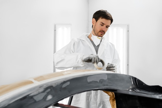 Male painter using gun to paint car in the shop