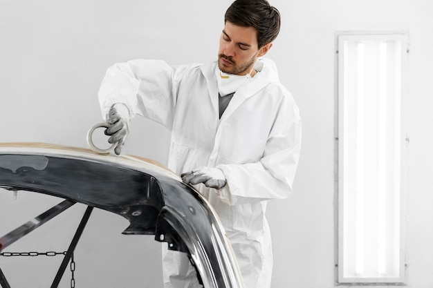 Male painter using gun to paint car in the shop