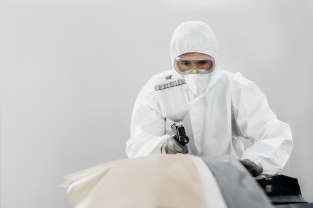 Male painter using gun to paint car in the shop