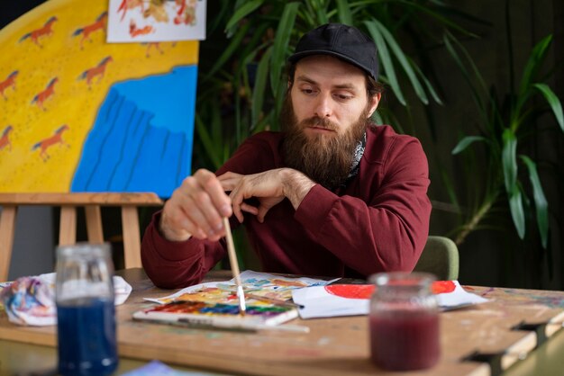 male painter using watercolor on his art in the studio