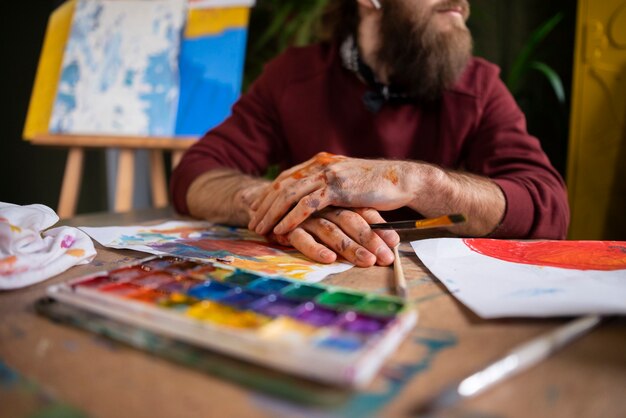 Foto gratuita pittore maschio che usa l'acquerello sulla sua arte in studio
