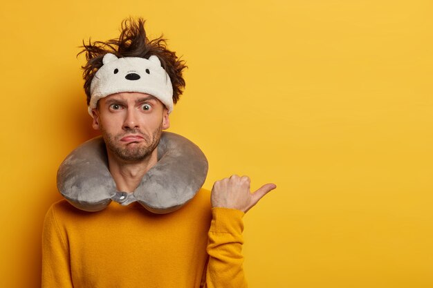 Male passenger wearing inflated travel pillow over neck and cute eye mask