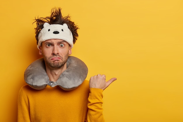 Male passenger wearing inflated travel pillow over neck and cute eye mask