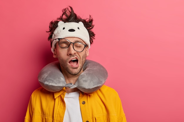 Male passenger wearing inflated travel pillow over neck and cute eye mask