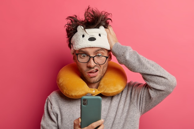 Male passenger wearing inflated travel pillow over neck and cute eye mask