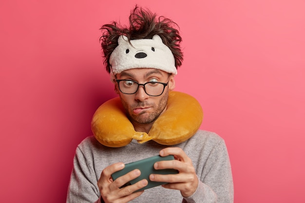 Male passenger wearing inflated travel pillow over neck and cute eye mask