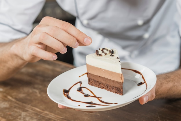 Male pastry chef decorating dessert in the kitchen