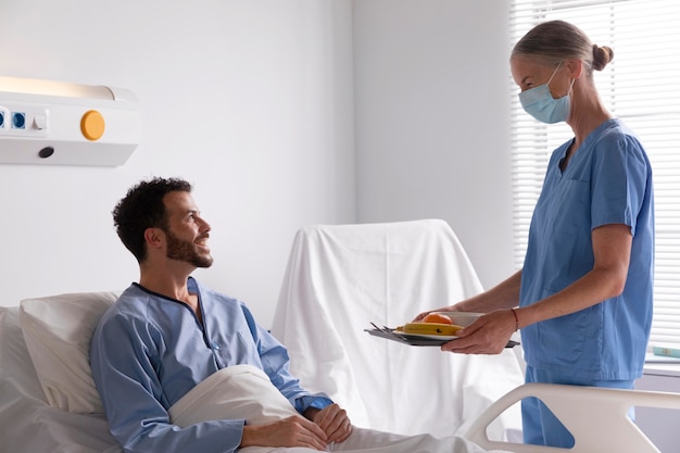 Male patient in bed talking to a nurse