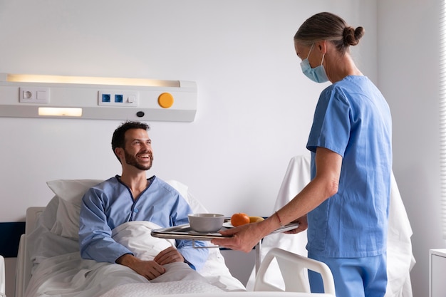 Male patient in bed talking to a nurse