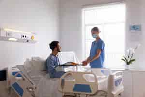 Free photo male patient in bed talking to a nurse