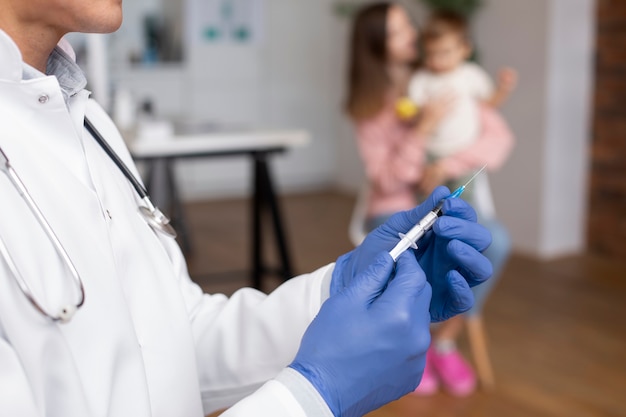 Male pediatrician administering vaccine in his office