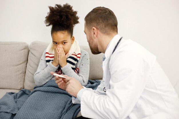 아픈 어린 흑인 소녀를 검사하는 남성 소아과 의사