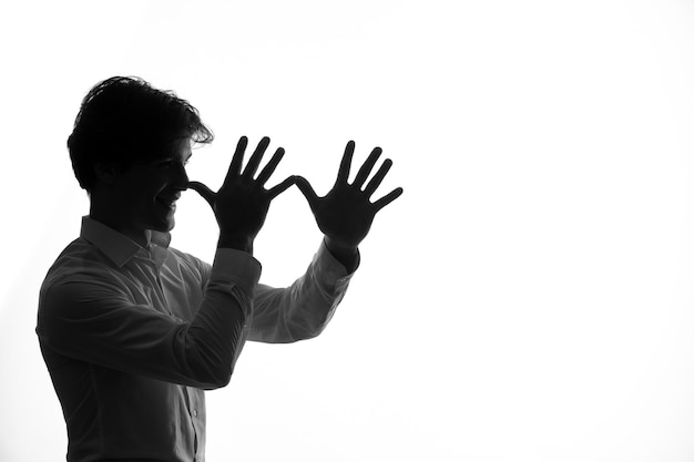 Male person silhouette in white clothing making funny faces shadow white background