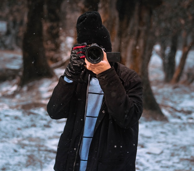 숲에서 겨울을 캡처하는 남성 사진 작가