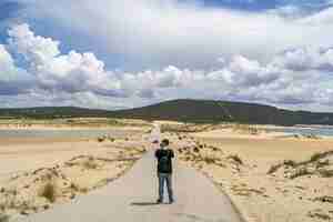 Free photo male photographer walking through a beach under a cloudy sky at daytime in andalusia, spain