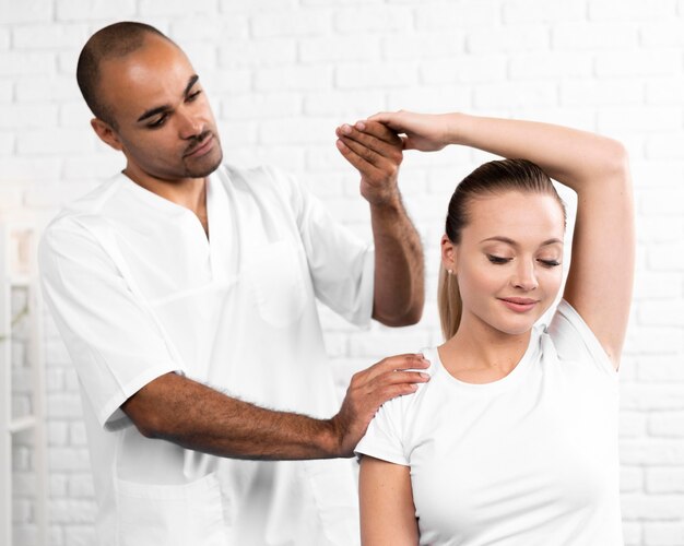 Male physiotherapist checking woman's arm flexibility
