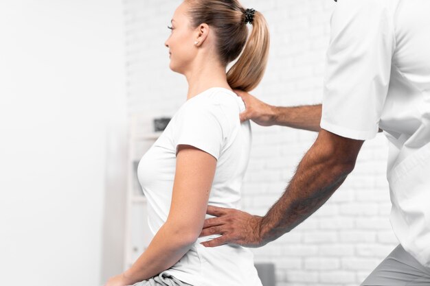 Мужской физиотерапевт, проверяющий женскую спину
