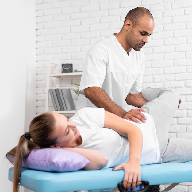Male physiotherapist checking woman's hip