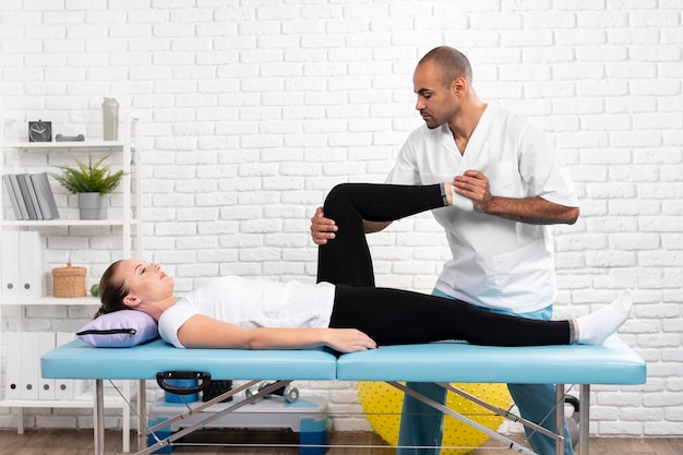 Male physiotherapist checking woman's leg