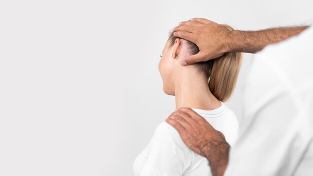 Male physiotherapist checking woman's neck pain