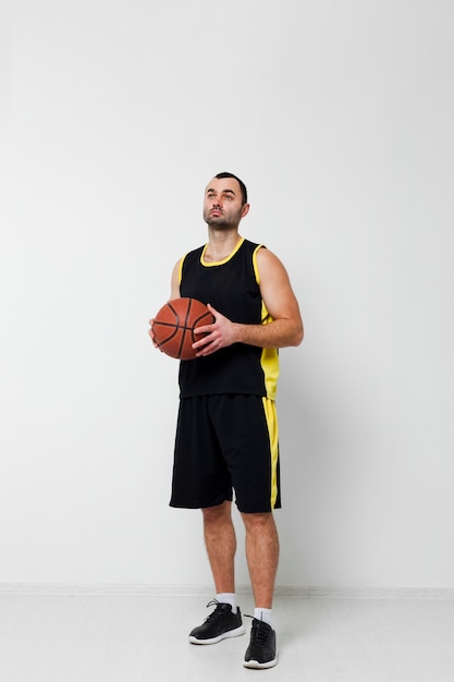 Male player posing while holding basketball with copy space