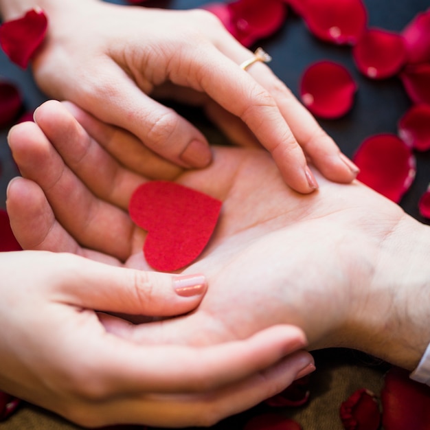 Male presenting red ornament heart to female