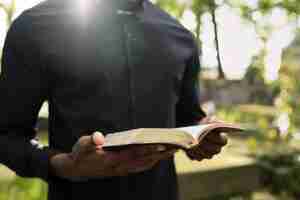 Free photo male priest reading from the bible at the grave with mourning family