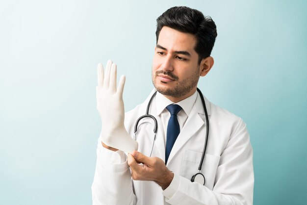 Male professional wearing glove while standing against blue background