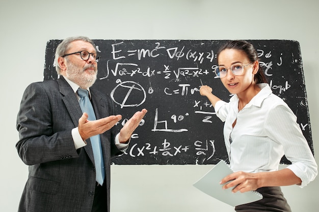 Male professor and young woman against chalkboard in classroom