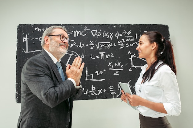 Male professor and young woman against chalkboard in classroom
