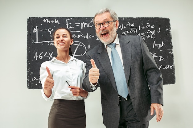 Free photo male professor and young woman against chalkboard in classroom