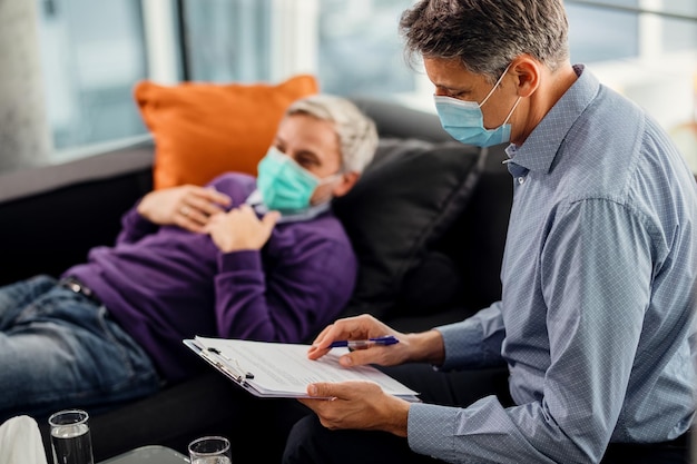 Male psychiatrist going through data of his patient while having appointment during coronavirus pandemic