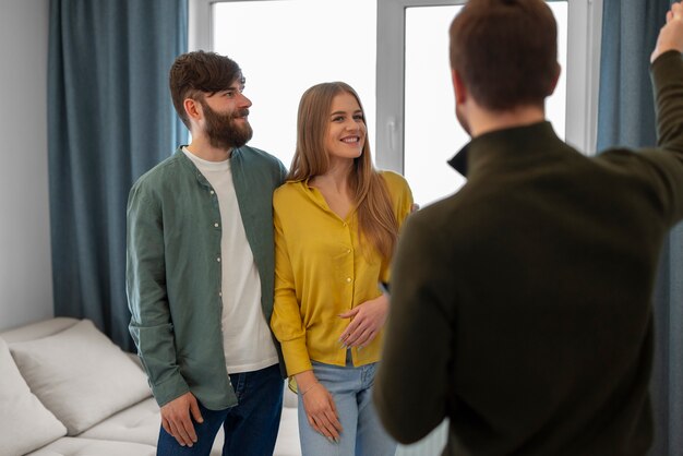 Male real estate agent doing business and showing house to potential buying couple