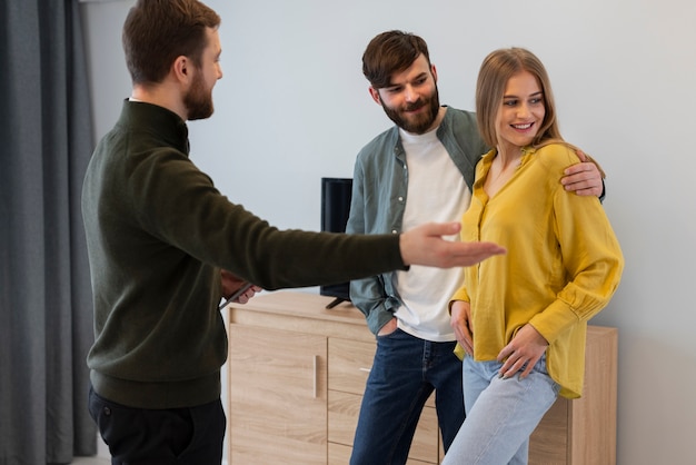 Free photo male real estate agent doing business and showing house to potential buying couple