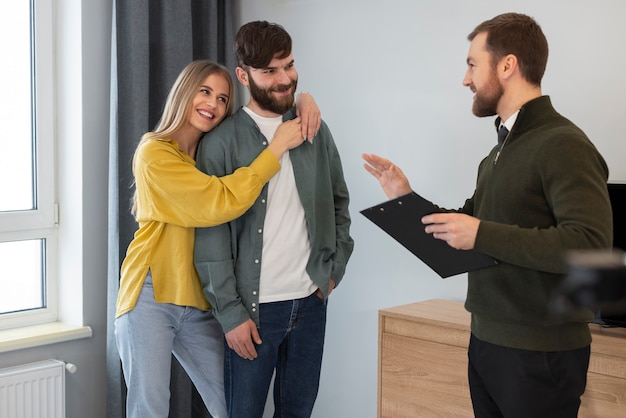 Male real estate agent doing business and showing house to potential buying couple