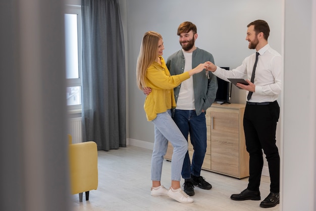 Мужчина-агент по недвижимости занимается бизнесом и показывает дом потенциальной паре покупателей