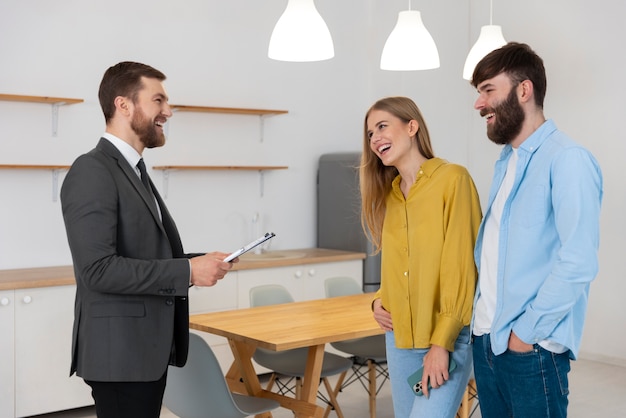 Free photo male real estate agent doing business and showing house to potential buying couple